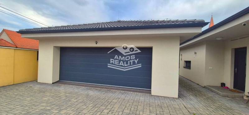 Garage mit Pflastersteinen bei einem Einfamilienhaus in Studienka, mit Steinpflaster und grauem Tor.