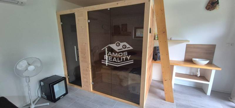 Innenraum eines Einfamilienhauses mit Sauna, Ventilator und Waschbecken auf einem Holztisch.