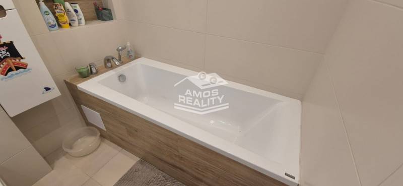 Ein Badezimmer mit einer mit Holzdekor verkleideten Badewanne in einem Einfamilienhaus.