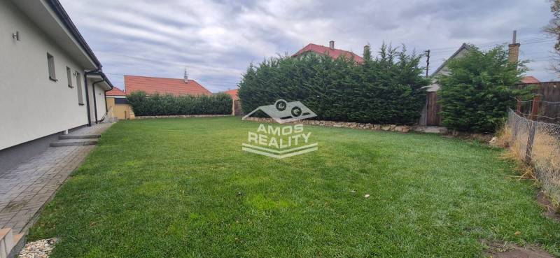 Ein Einfamilienhaus in Studienka mit Garten, gepflegtem Rasen und hohem lebenden Zaun.