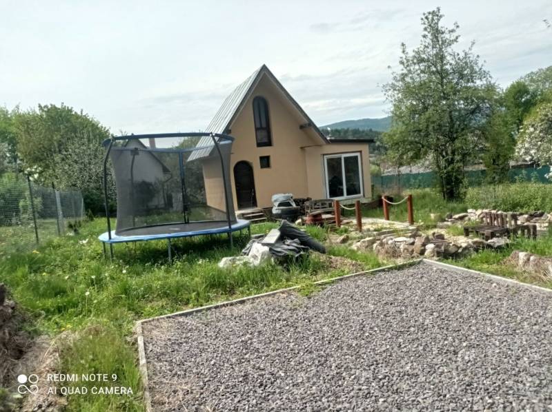 Eine Hütte in Hliník nad Hronom mit einem Trampolin und einem steinigen Weg im Garten.