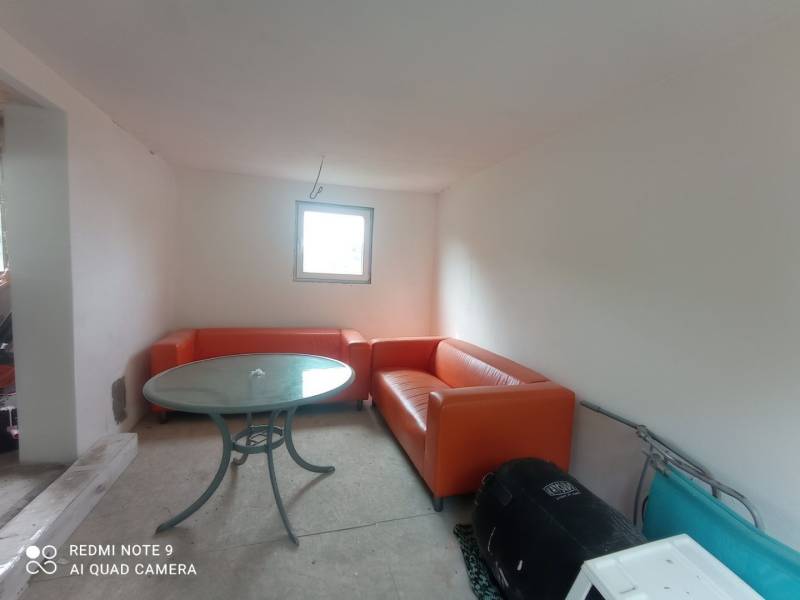 Orangefarbene Sofas und ein runder Tisch ergänzen den Raum in einer Hütte mit weißen Wänden.