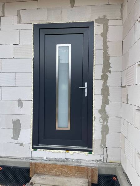 Eingangstür eines Einfamilienhauses in Radava, umgeben von Ziegelmauerwerk.