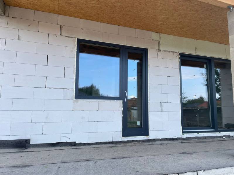 Unvollendete Fassade eines Einfamilienhauses in Radava mit Kunststofftüren und -fenstern.