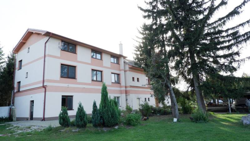 Das Gebäude des Hotels und der Pension in Poľný Kesov, umgeben von Grün und Bäumen.