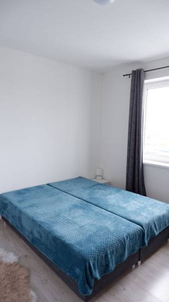 Schlafzimmer in einem Einfamilienhaus mit blauen Überwürfen auf dem Bett und Jalousien.