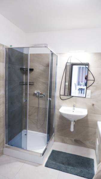 Ein Badezimmer in einem Einfamilienhaus mit einer Eckdusche und einem unkonventionellen Spiegel.