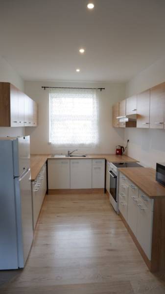 Küche in einem Einfamilienhaus mit weißen Schränken und einem Boden in Holzoptik.