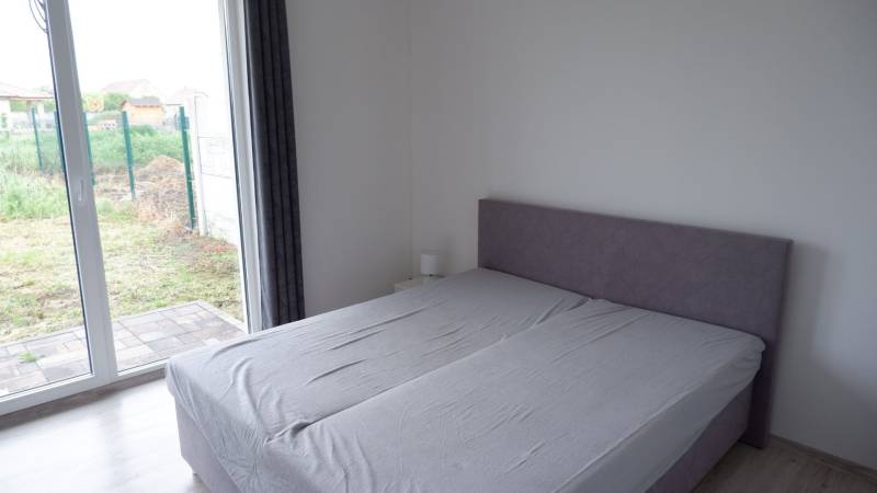 Ein Schlafzimmer in einem Einfamilienhaus mit einem Bett und großen bodentiefen Fenstern mit Holzdekor.