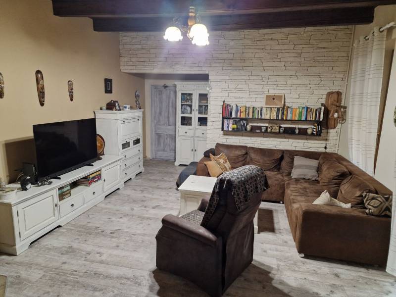 Wohnzimmer mit Ecksofa, weißen Möbeln und Boden in Holzoptik in einem Einfamilienhaus.