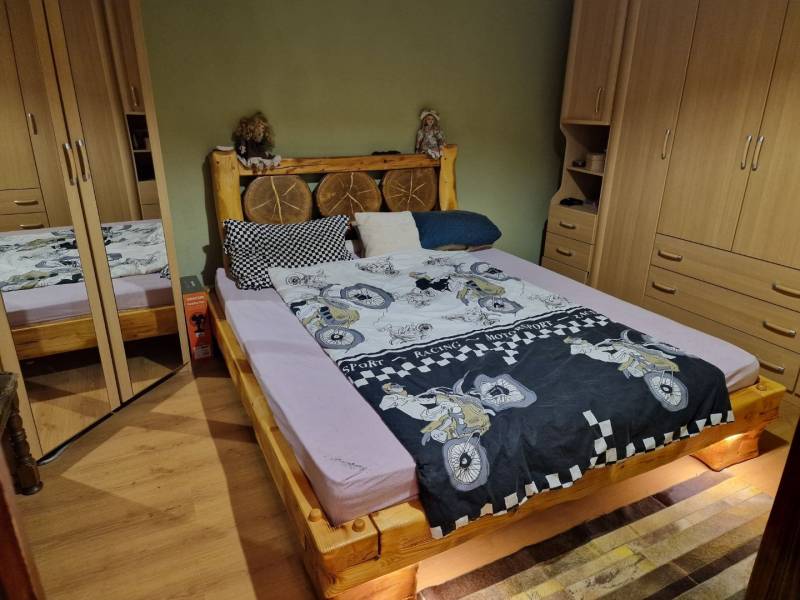 Ein Schlafzimmer in einem Einfamilienhaus mit einem Holzbett, Einbauschränken und einem Boden mit Holzdekor.