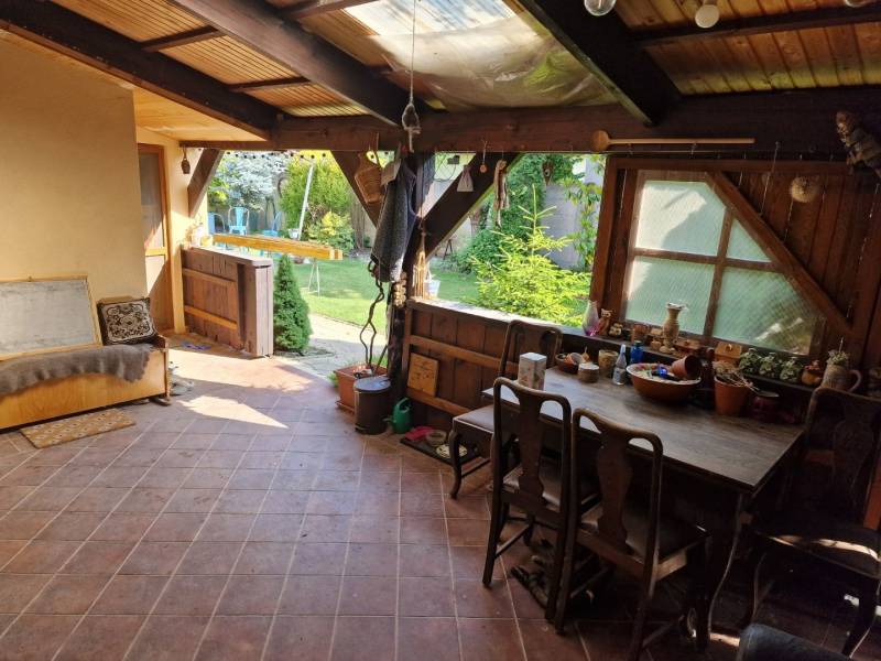 Rustikale Terrasse eines Einfamilienhauses mit Holzmöbeln und Blick auf den Garten.