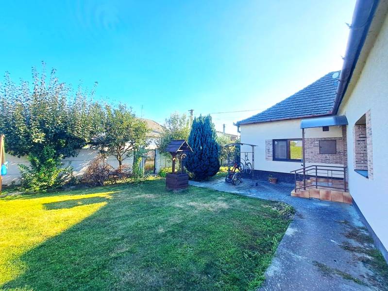 Ein Einfamilienhaus in Neded mit einem gepflegten Garten, Rasen und einem Pavillon neben dem Haus.
