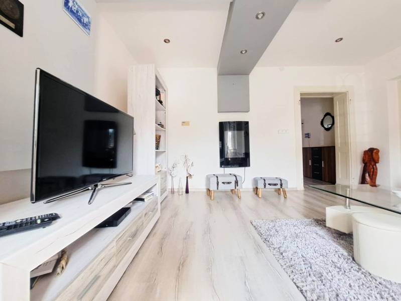 Wohnzimmer in einem Einfamilienhaus mit Fernseher und Holzboden.