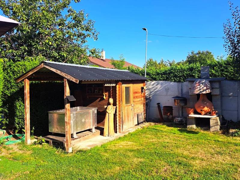 Der Garten eines Einfamilienhauses in Neded mit einem Holzhaus und einem Außenkamin.