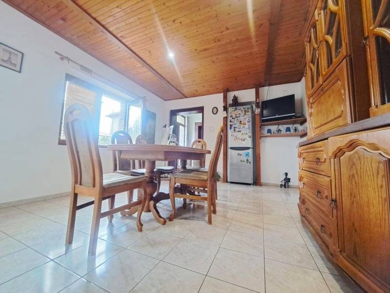 Esszimmer in einem Einfamilienhaus mit Holzbalkendecke und Fliesenboden.