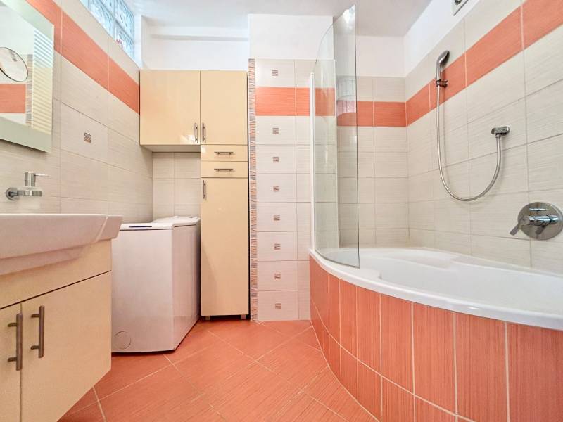 Badezimmer in einer 2-Zimmer-Wohnung mit Badewanne, Waschmaschine und Stauraum.