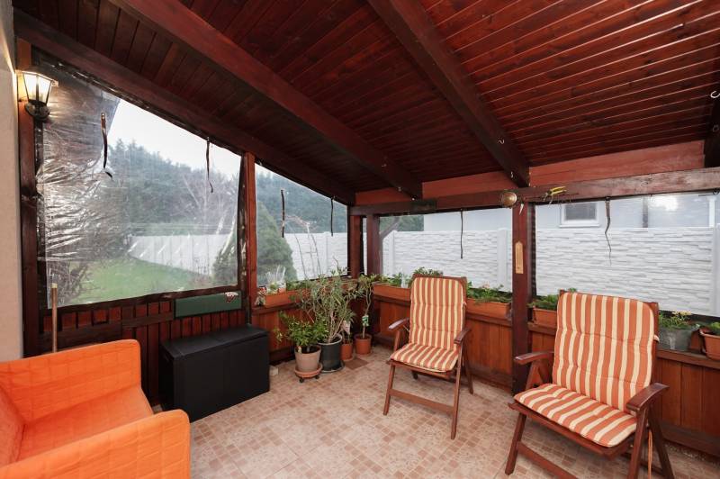 Wintergarten eines Einfamilienhauses mit Stühlen und Pflanzen, Boden mit Fliesen.