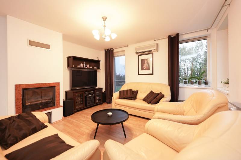 Wohnzimmer in einem Einfamilienhaus mit Kamin, Ledersofas und einem Boden in Holzoptik.