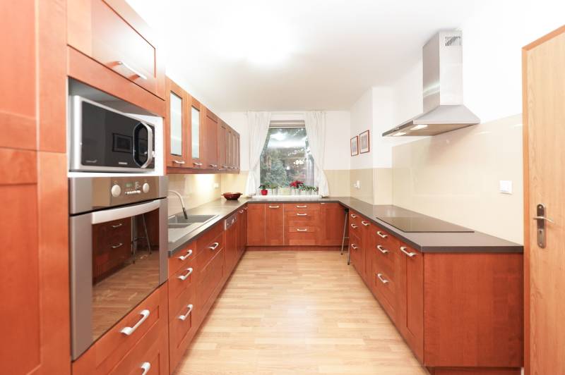 Küche in einem Einfamilienhaus mit Holzdekor, mit Kochfeld und Mikrowelle.