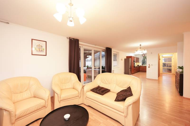 Wohnzimmer eines Einfamilienhauses mit cremefarbenem Sofa und Boden in Holzoptik.