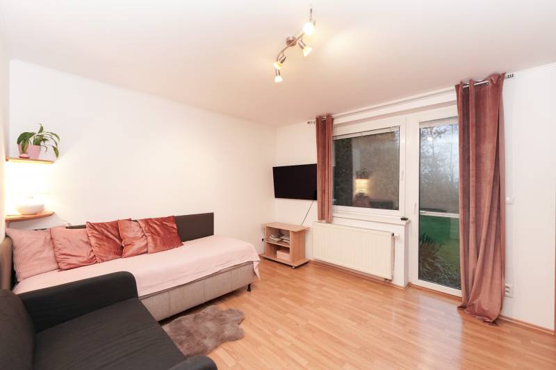 Wohnzimmer in einem Einfamilienhaus mit Sofa, Fernseher und Boden in Holzoptik.