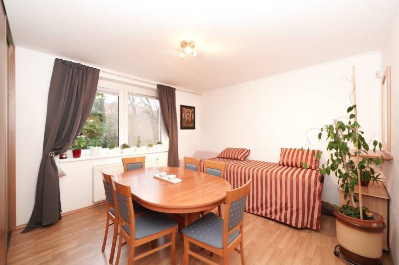 Esszimmer in einem Einfamilienhaus mit rundem Tisch, Sesseln, Sofa und Boden in Holzoptik.