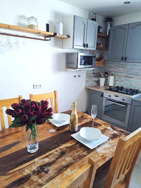 Küche in einem Einfamilienhaus mit Holztisch, Blumen, Champagner und Küchenzeile.