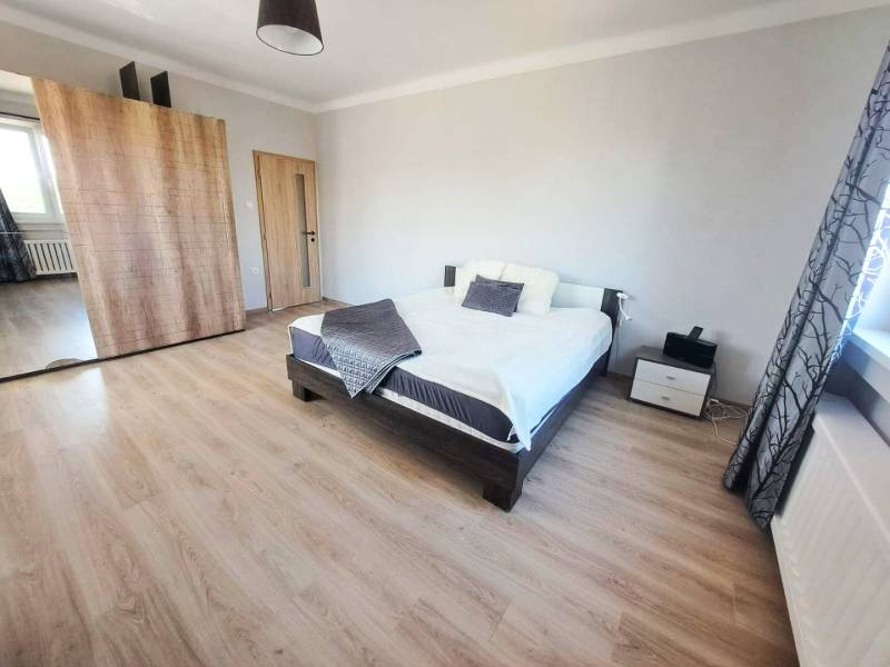 Schlafzimmer in einem Einfamilienhaus mit Bett, Kleiderschrank und Boden mit Holzdekor.