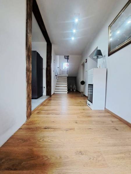 Innenraum eines Einfamilienhauses mit Holzboden und Treppe im Hintergrund.