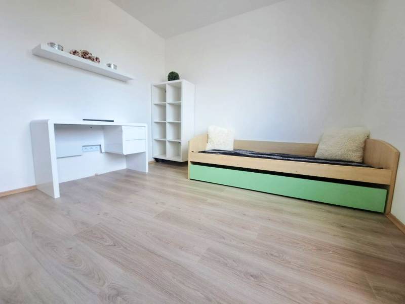 Ein Zimmer in einem Einfamilienhaus mit einem weißen Tisch, einem Bett und einem Boden mit Holzdekor.