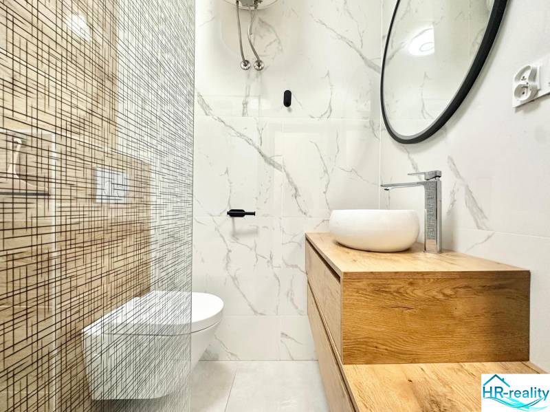 Badezimmer in einer Ferienwohnung mit minimalistischem Design und markantem Holzdekor.