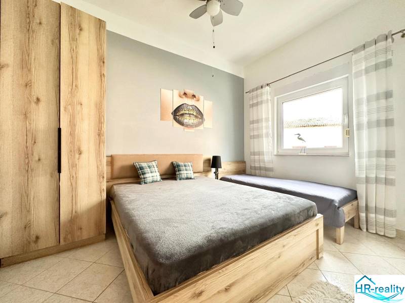 Helles Schlafzimmer mit Holzmöbeln, Doppelbett und Bild in einer Ferienwohnung.