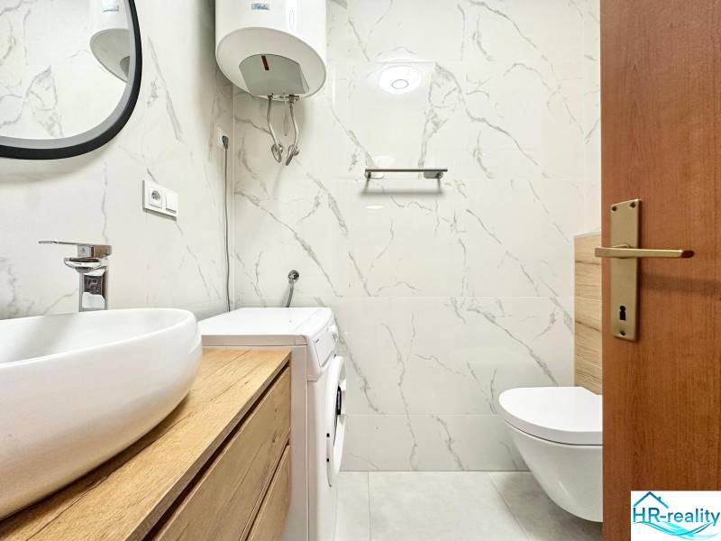 Badezimmer in einer Ferienwohnung mit Toilette, Waschmaschine und Waschbecken in Holzdekor.