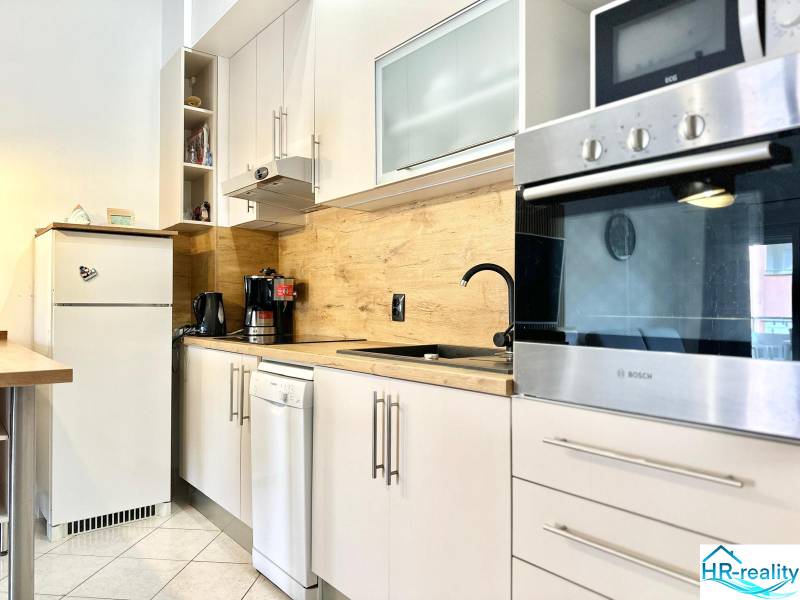 Küche in der Ferienwohnung mit weißen Möbeln und Holzwanddekor.