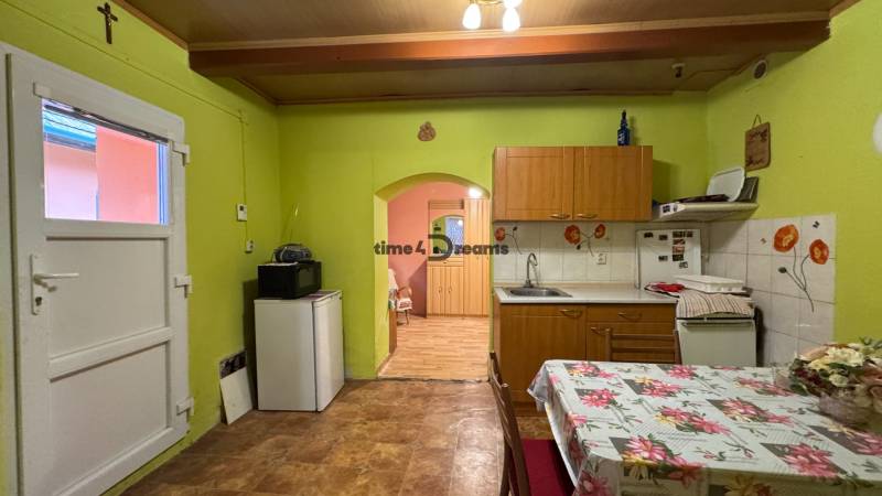 Küche in einem Einfamilienhaus mit grünen Wänden, einem Blumen-Tischtuch und Holzboden-Dekor.