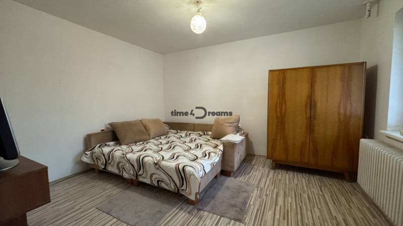 Schlafzimmer eines Einfamilienhauses mit Bett, Kleiderschrank und Boden in Holzoptik.