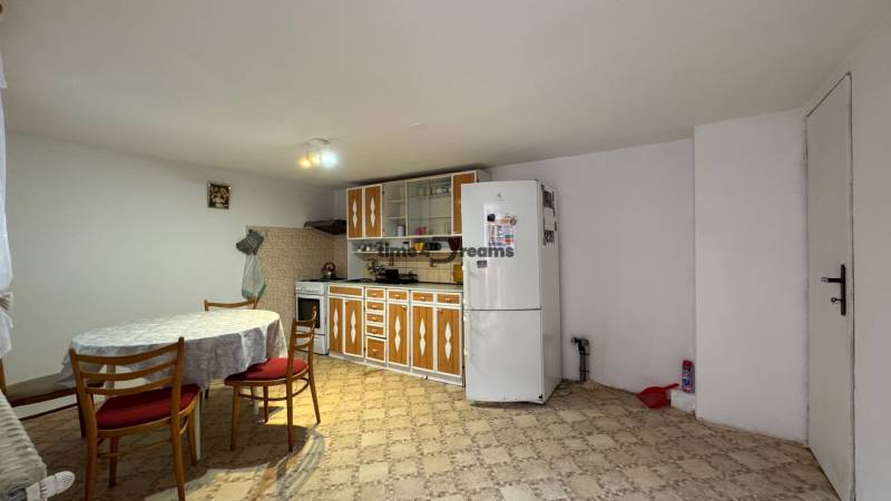 Eine Küche in einem Einfamilienhaus mit einem Esstisch, älterer Einrichtung und hellen Wänden.