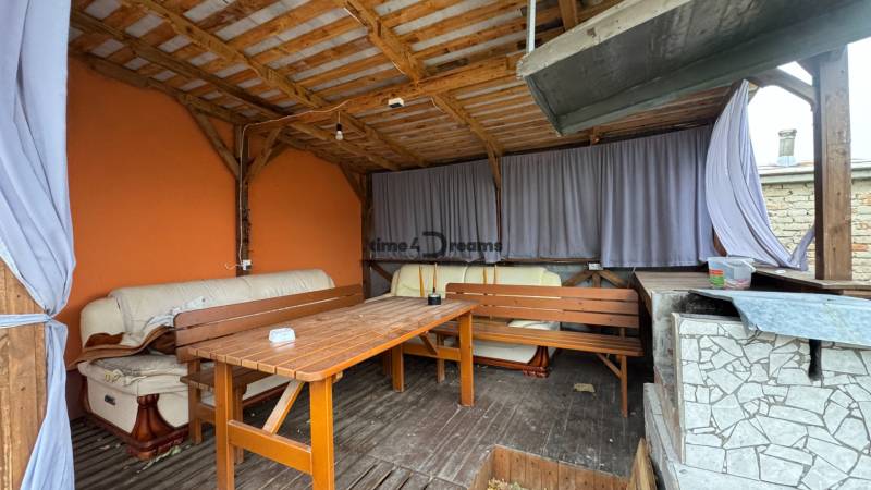 Hinter dem Einfamilienhaus in Čechynce befindet sich eine überdachte Terrasse mit Sitzgelegenheiten und einer orangefarbenen Wand.