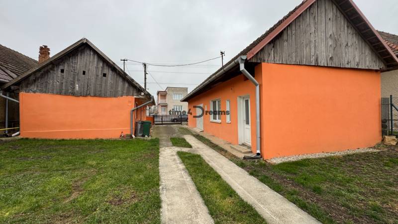 Ein Einfamilienhaus in Čechynce mit einer orangefarbenen Fassade, einem Hof und Wirtschaftsgebäuden.