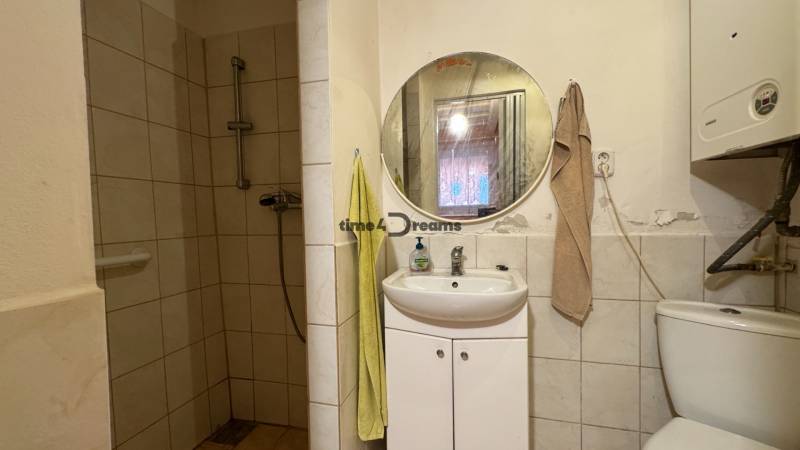 Badezimmer in einem Einfamilienhaus mit Toilette, Duschkabine und rundem Spiegel.