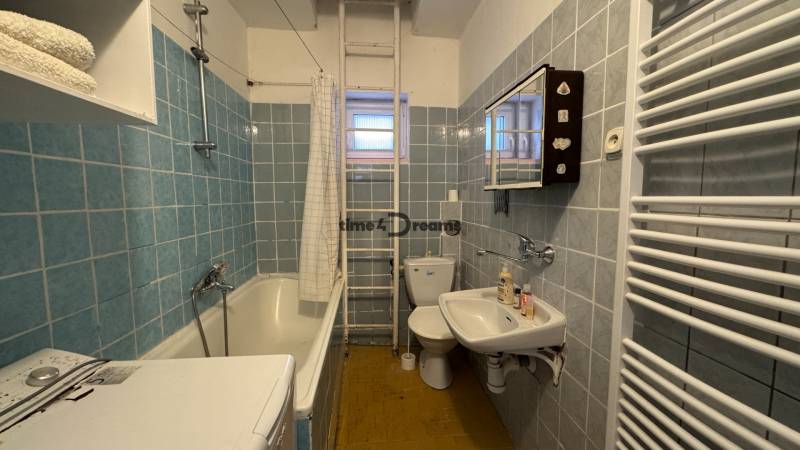 Ein Badezimmer in einem Einfamilienhaus mit einer Badewanne, einer Waschmaschine und blauen Fliesen.