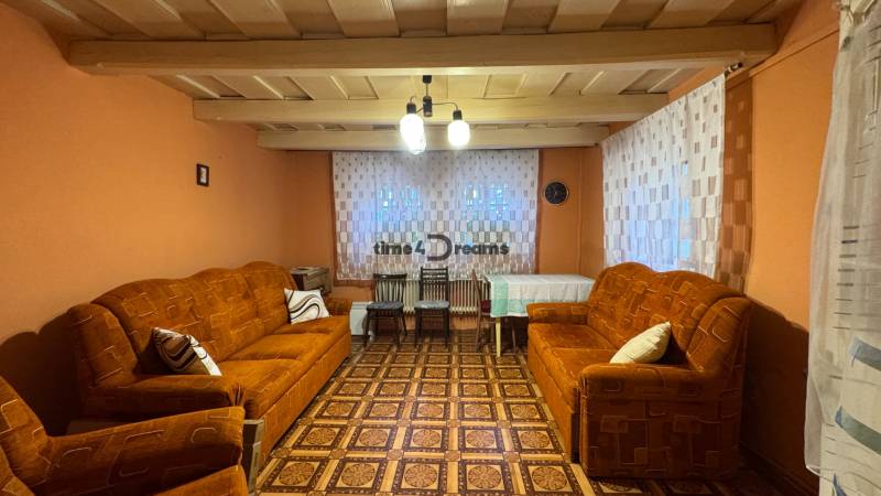 Wohnzimmer in einem Einfamilienhaus mit orangefarbenen Sofas und einem Boden in Holzoptik.