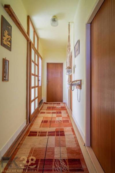 Ein Flur in einem Einfamilienhaus mit Teppichboden, Holztüren und Wanddekorationen.