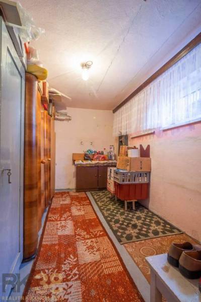 Úložný priestor v rodinnom dome s kobercami, policami a krabicami.