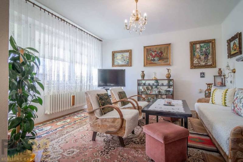 Wohnzimmer in einem Einfamilienhaus mit Sofa, Fernseher und Bildern an den Wänden.