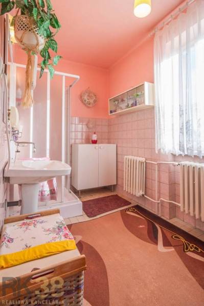 Ein Badezimmer in einem Einfamilienhaus mit Fliesen und einer Duschkabine, hellrosa Wände.