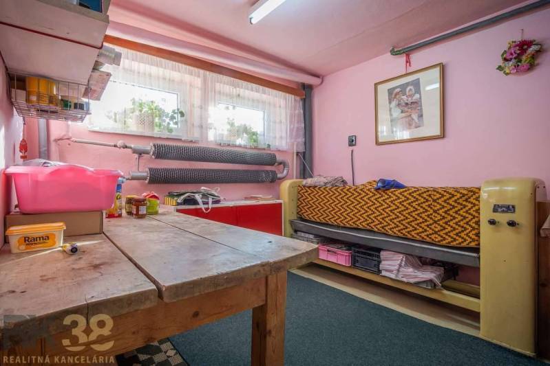 Ein Zimmer in einem Einfamilienhaus mit rosa Wänden, einem Holztisch und einem Bett.
