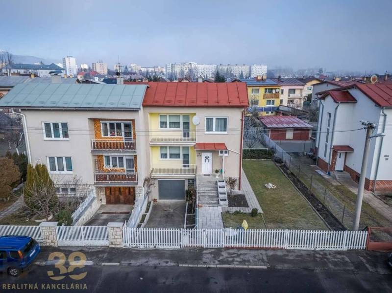 Ein Einfamilienhaus in Poprad mit Doppeldächern, einem weißen Zaun und einem gepflegten Garten.