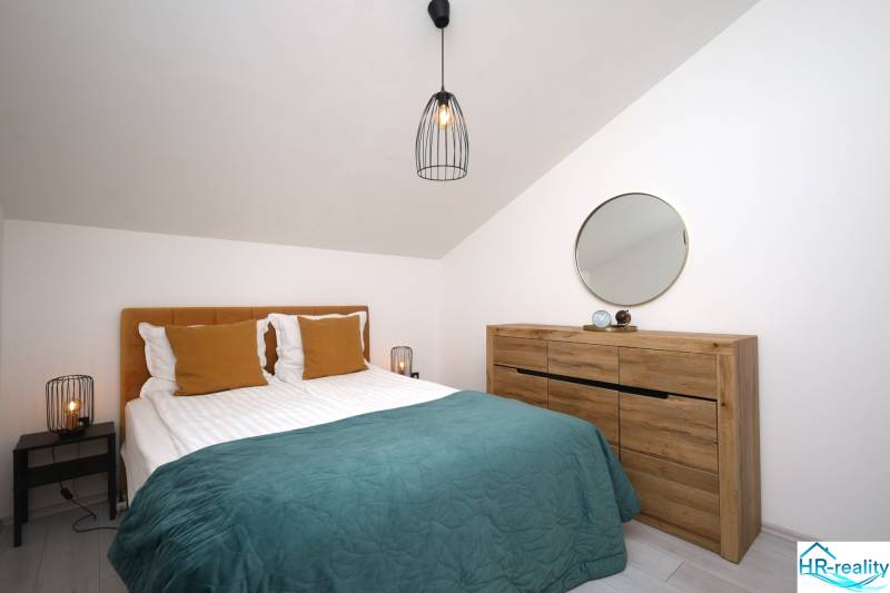 Schlafzimmer in einer Ferienwohnung mit Bett, Holzkiste, Spiegel und Lampe.